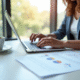 Personne utilisant un ordinateur portable dans un bureau lumineux avec documents multilingues